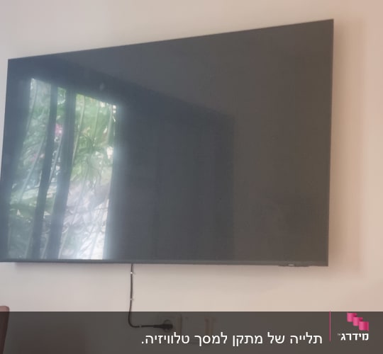 טלוויזיה תלויה על הקיר עם כבל חשמל מחובר